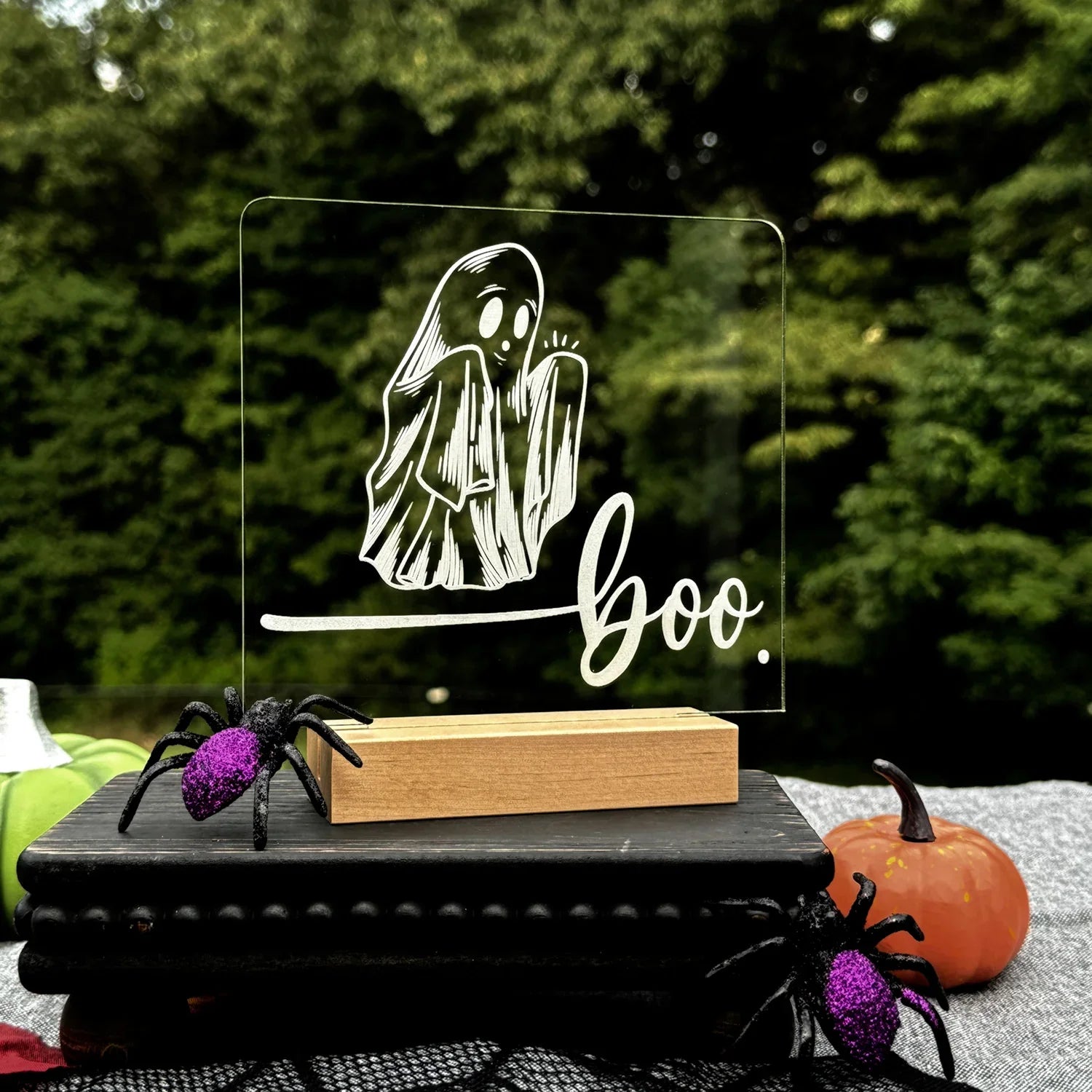 Halloween "Boo" LED Nightlight with ghost design on acrylic light in wooden base, surrounded by spooky decorations.