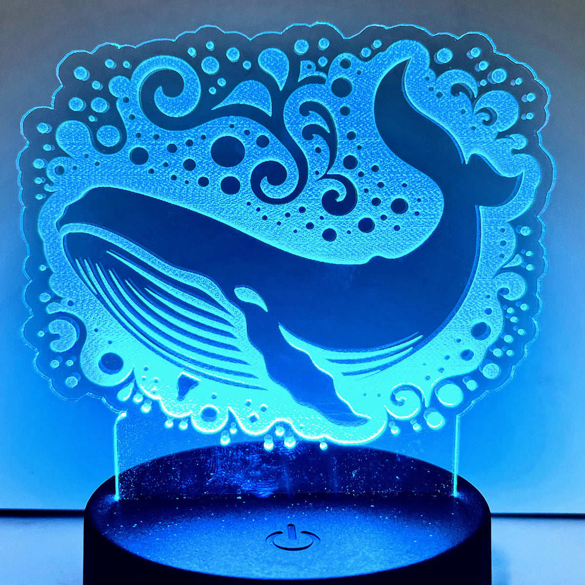 Sea whale LED nightlight glowing on a compatible base, with marine-inspired design.