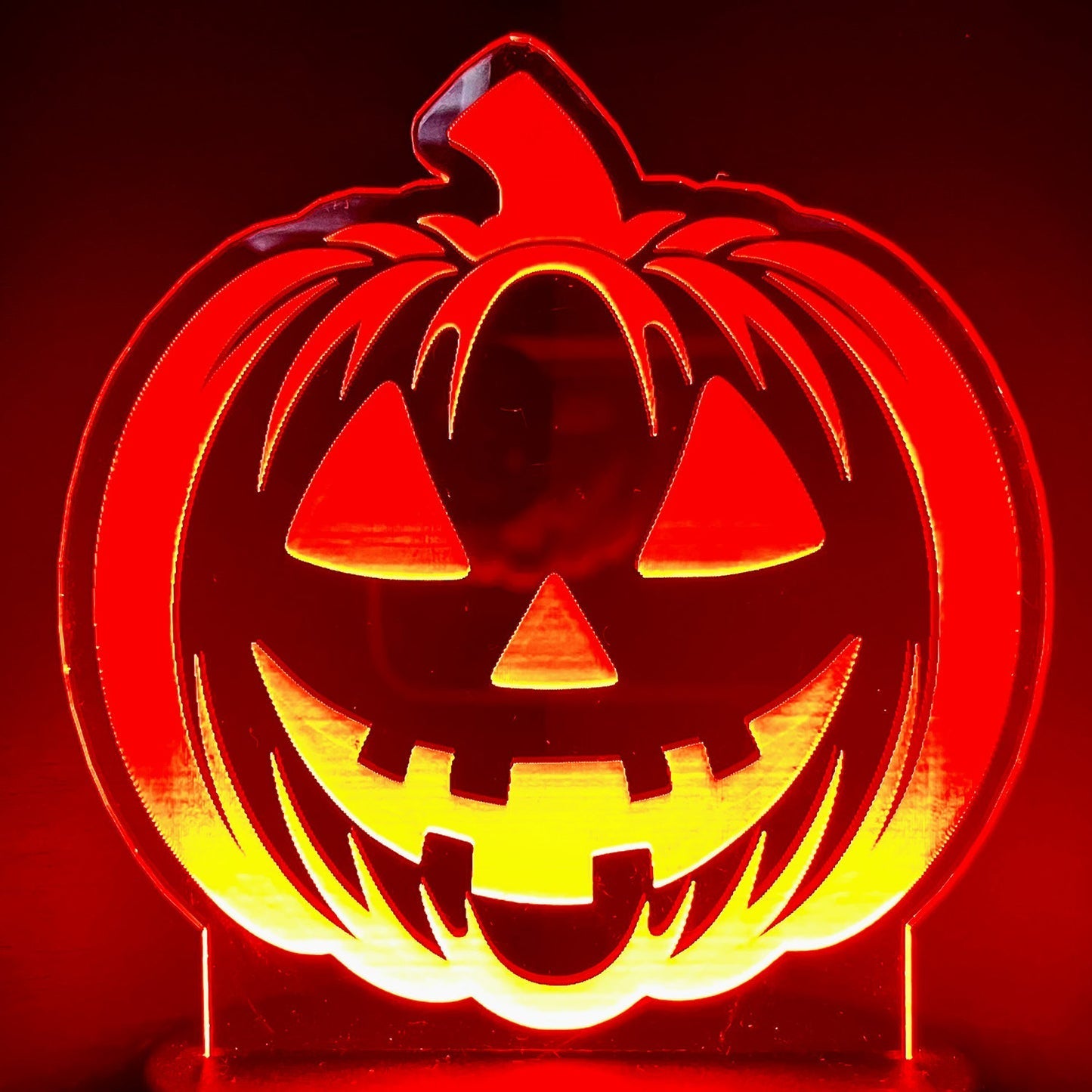 Smiling Jack-O-Lantern LED nightlight illuminating in red and yellow.